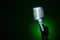 Studio retro condenser microphone on green spot light background