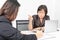 Studio shot of Asian, senior businesswoman with laptop, sitting with two young staffs in board room in office, boss making serious