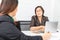 Studio shot of Asian, senior businesswoman with laptop, sitting with two young staffs in board room in office, boss making serious