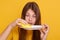 Studio shot of astonished girl with dirty plate and sponge in hands, poses with big eyes, posing isolated over yellow background,