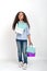 Studio shot of attractive little girl of mulatta with long frizzy. She goes shopping in paper shopping bags and puzzles her