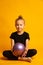 Studio shot of attractive little gymnast girl blonde wearing black legends and a bathing suit with a purple ball