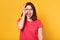 Studio shot of attractive young woman, makes ok sign and covers her eye, shows tongue, expresses happyness, model poses against