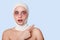 Studio shot of beautiful woman before plastic surgery with bandage on head with shocked facial expression, points fore finger to
