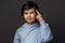 Studio shot of boy 10-12 years old pointing with finger at head. Concept of thinking. Studio shot, gray background