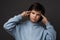 Studio shot of boy 10-12 years old pointing with fingers at head. Concept of thinking. Studio shot, gray background