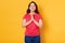 Studio shot of brunette woman prays for something, wishing good luck, has faith for better, posing with closed eyes and toothy