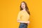 Studio shot of cheerful beautiful Asian woman in t-shirt and stand on yellow background