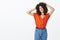 Studio shot of chill outgoing african american woman with afro hairstyle holding hands on back of head and gazing at