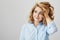 Studio shot of dreamy attractive woman with short curly hair looking aside with tender smile, touching haircut and