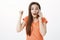 Studio shot of excited overwhelmed attractive woman, turning at camera with raised fist, talking on smartphone