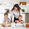 Studio shot of a family in the kitchen at home. Small children, a girl and a boy, learn to make dough rolls with their mother or