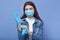 Studio shot of female posing isoalted over blue background, young woman putting on blue disposable latex gloves, satnding dresses