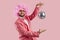 Studio shot of funny man in pink suit, clown wig and disco glasses holding mirror ball