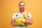 Studio shot of good looking screaming man with bald head, hugs cleaning detergents, wears t shirt,  over yellow background