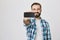 Studio shot of handsome caucasian man with beard and moustache holding smartphone in stretched hand with focus on it