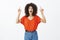 Studio shot of impressed satisfied good-looking african-american woman with afro hairstyle in trendy outfit, looking and