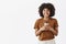 Studio shot of joyful carefree and friendly African American happy woman with afro hairstyle holding cup of coffee in