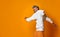 Studio shot of modern, hipster businessman pretends dancing, isolated on orange background