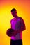 Studio shot of muscled man, basketball player, danker  on gradient yellow purple background in neon light