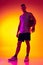 Studio shot of muscled man, basketball player, danker isolated on gradient yellow purple background in neon light