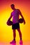 Studio shot of muscled man, basketball player, danker isolated on gradient yellow purple background in neon light