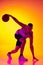 Studio shot of muscled man, basketball player training with ball isolated on gradient yellow purple background in neon
