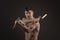 Studio shot of a muscled man in single combat weapon pose with nunchaku on a black background