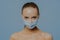 Studio shot of naked European woman wears disposable medical mask as prevention fromm coronavirus has makeup combed hair poses