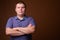 Studio shot of overweight young man against brown background