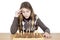 Studio Shot Of Pensive Young Girl Looking Down At Chessboard And Thinking Intensely About Chess Strategy Isolated On White