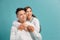 Studio shot of romantic couple posing with smile. Front view of girl and boy hugs on blue background