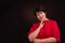 Studio shot of a senior adult serious woman wearing a red dress on a dark background. She calmly looks at the camera with her