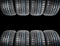 Studio shot of a set of summer car tires on black background. Tire stack background. Car tyre protector close up. Black rubber tir