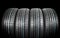 Studio shot of a set of summer car tires on black background. Tire stack background. Selective focus. Car tyre protector close up.