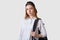 Studio shot of student girl isolated over white background wearing blouse and backpack, looking upset, female studies at collage,