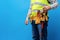 Studio shot of unknown handyman with hands on waist and tool belt with construction tools