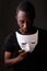 Studio shot of young black African man in dark room holding mask