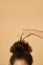 Studio shot of young mixed race woman with highly raised dark curly hair fixing her hairstyle, posing isolated over