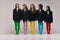 Studio shot of young stylish beautiful fashion models in black jackets and multi colored tights posing over grey