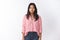 Studio shot of young vietnamese female in pink striped blouse and jeans standing relaxed as staring at camera focused