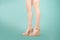 Studio shot of a young woman`s legs in a pair of pink platform wedge shoes on turquoise