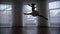 A studio in twilight. A silhouette of ballerina runs up and jumps performing a split in the air.