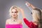 Studio worker applying a hair spray over beautiful blonde\'s hair wearing pink dress and necklace