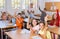 Studious preteen pupils raising hands to answer in class