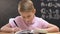 Studious pupil writing test work, school lessons, math equation on blackboard