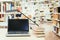 Studying in the university: Laptop on a wooden desk, pile of books and books in the blurry background