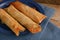 Stuffed filo or yufka dough rolls with a spicy meat filling on a blue plate on a rustic wood, selected focus