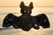 Stuffed funny Black Bat toy at the sunrise in front of the lake. A Symbol of Rebirth. Guardian of the Night