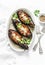 Stuffed lentils roasted eggplant - delicious healthy vegetarian served lunch table. On a light background